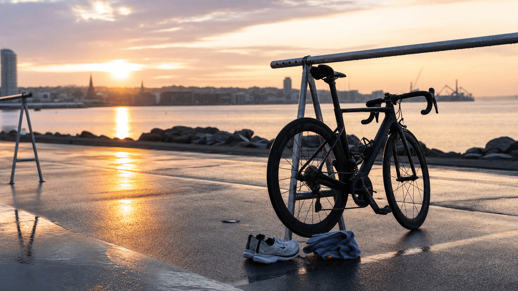 Unbranded sprint triathlon bike and transition gear beside Aarhus Bay at sunrise