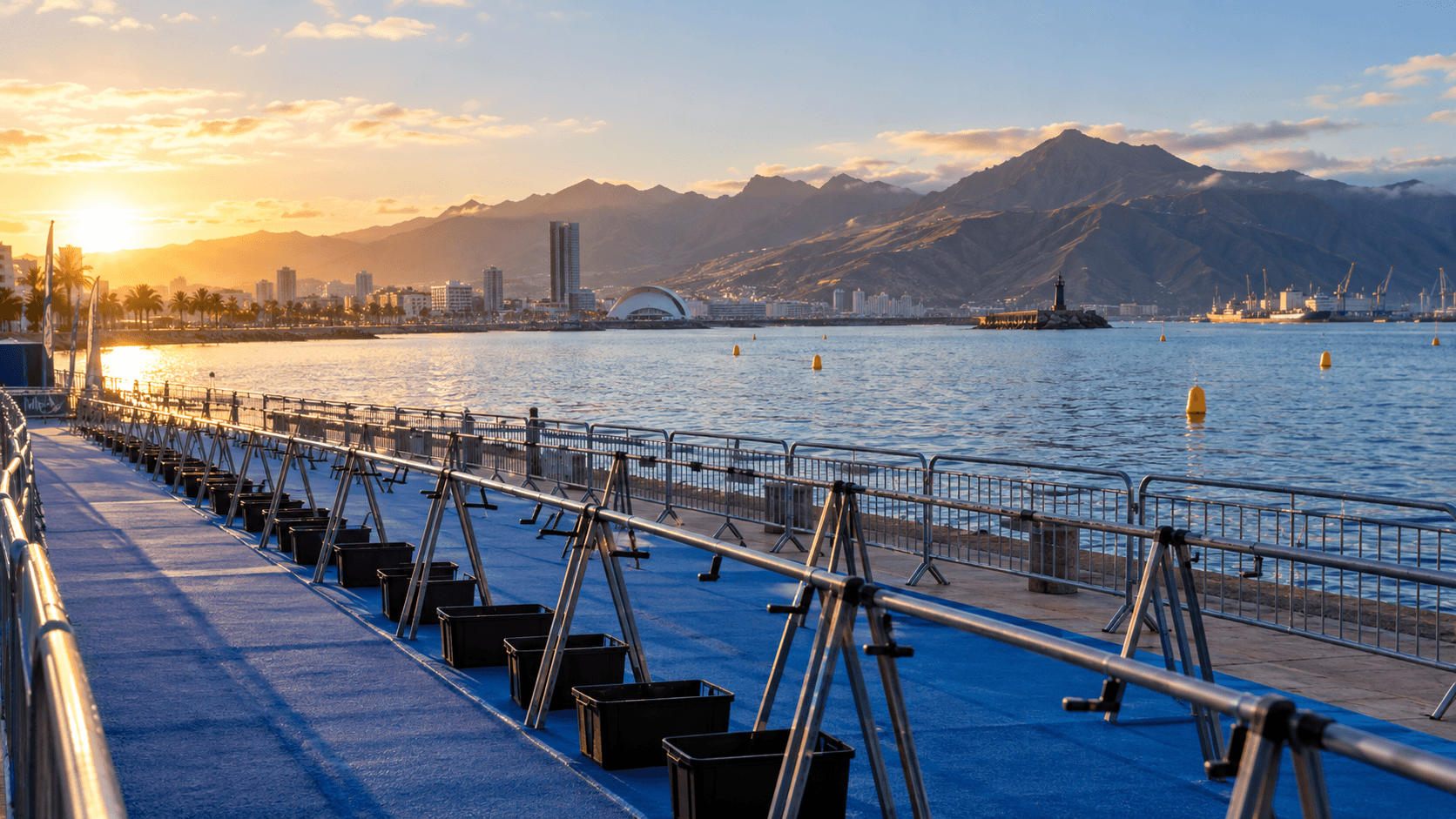 A quiet Atlantic waterfront triathlon course in Tenerife, with an empty transition area and volcanic ridgeline in morning light.