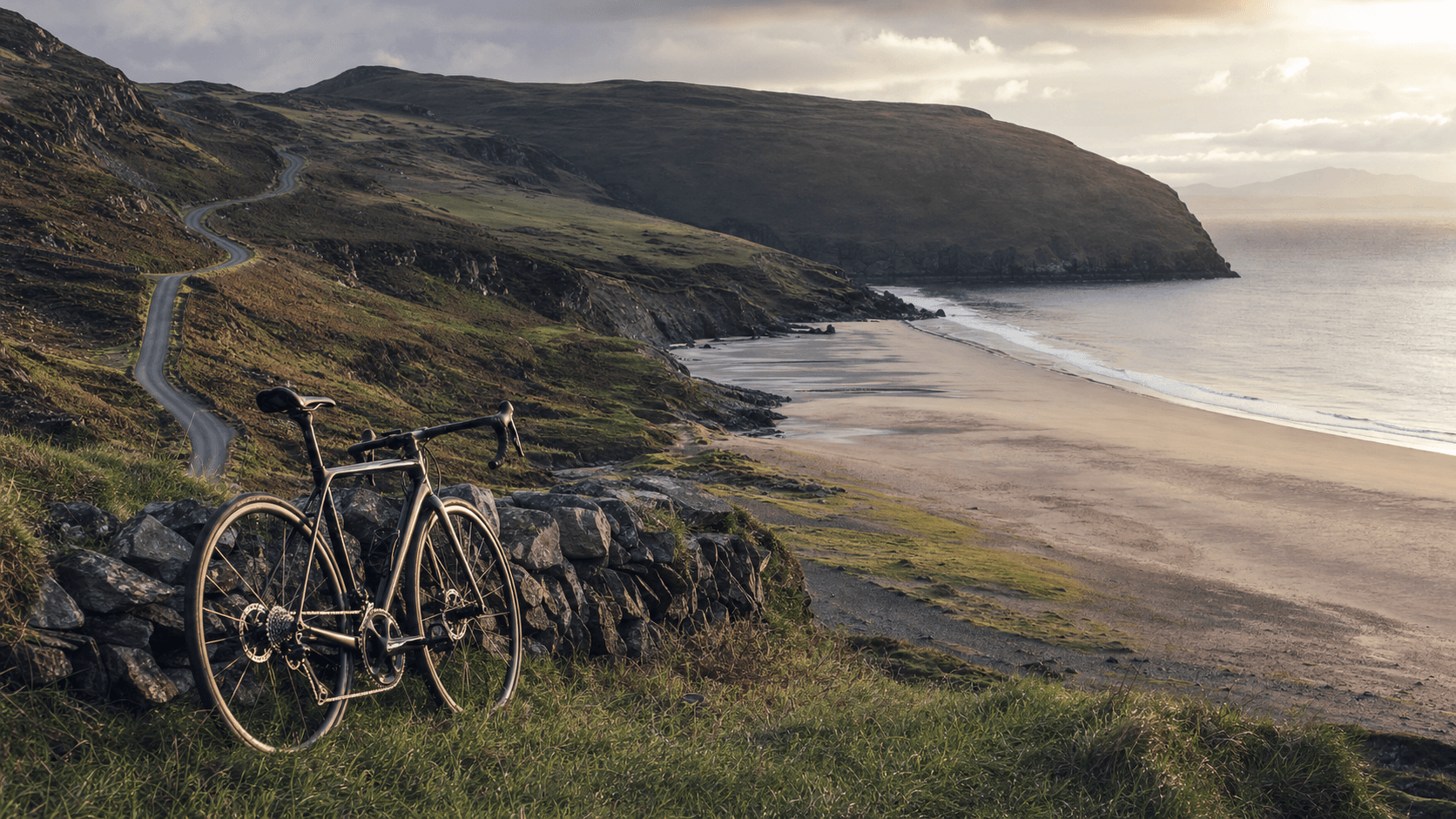 Welsh seaside bay and hilly coastal road at dawn