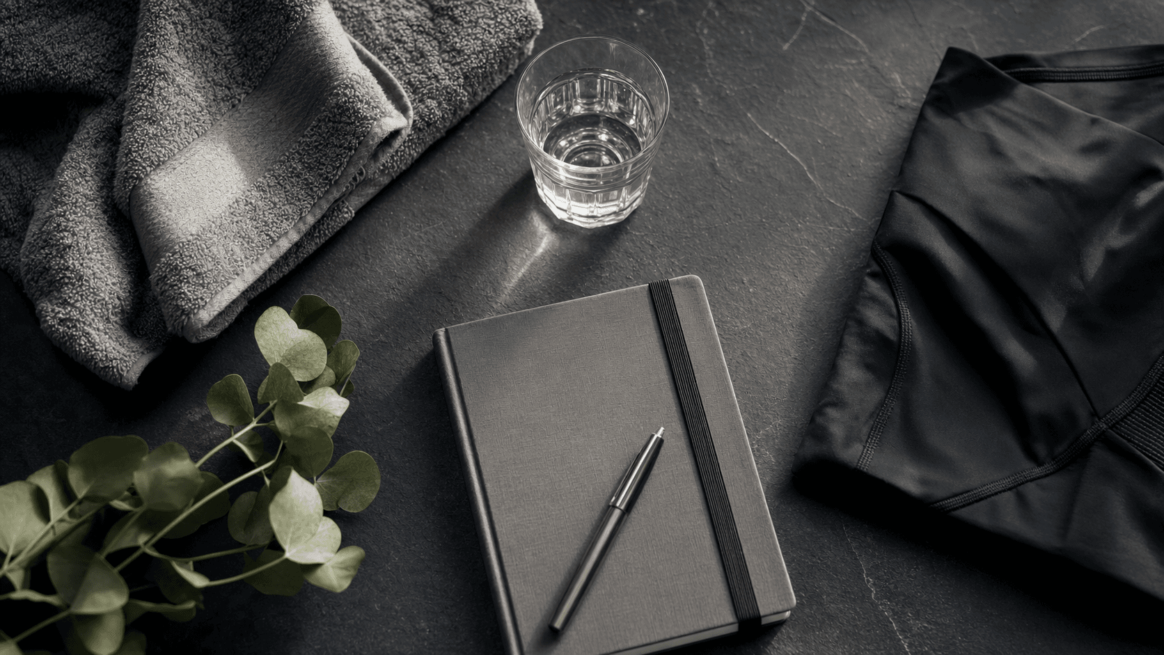 Unbranded recovery flat-lay with towel, water glass, training journal and folded compression garment